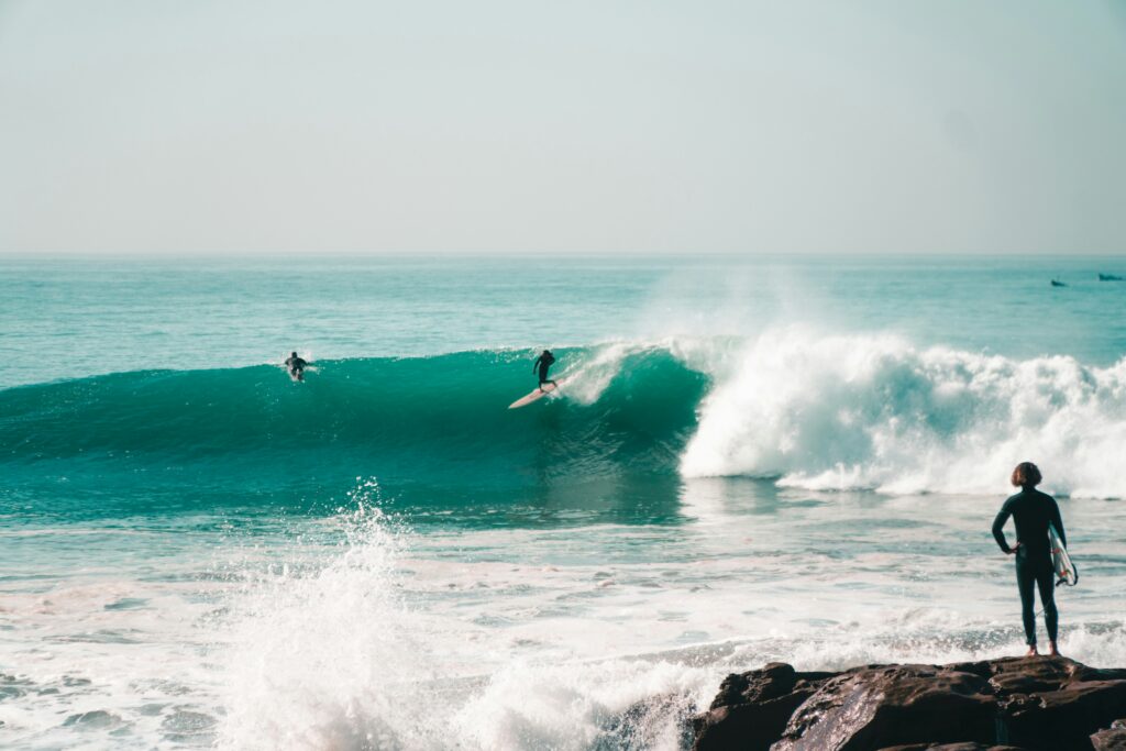 Surfer catching a clean right-hand wave during a perfect sunny day in Taghazout, Morocco — showcasing the ideal conditions for surf in Taghazout, one of the most popular surf destinations in North Africa.
